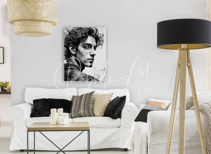 Black-and-white portrait canvas of a man with curly hair and intense gaze titled Bad Boy, mounted on a light gray wall