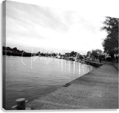 Black and white canvas print of cloudy dawn featuring a waterfront marina with boats docked along a concrete pier