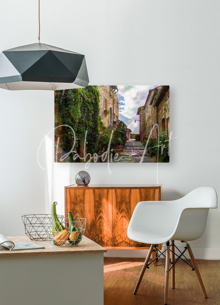 A rectangular canvas print titled cobblestone steps and stones to the sky showing a sunlit european village street with ivy-covered stone buildings