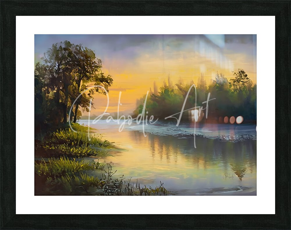 Framed landscape painting as the dawn breaks showing a serene sunset over water with golden hues and tree reflections