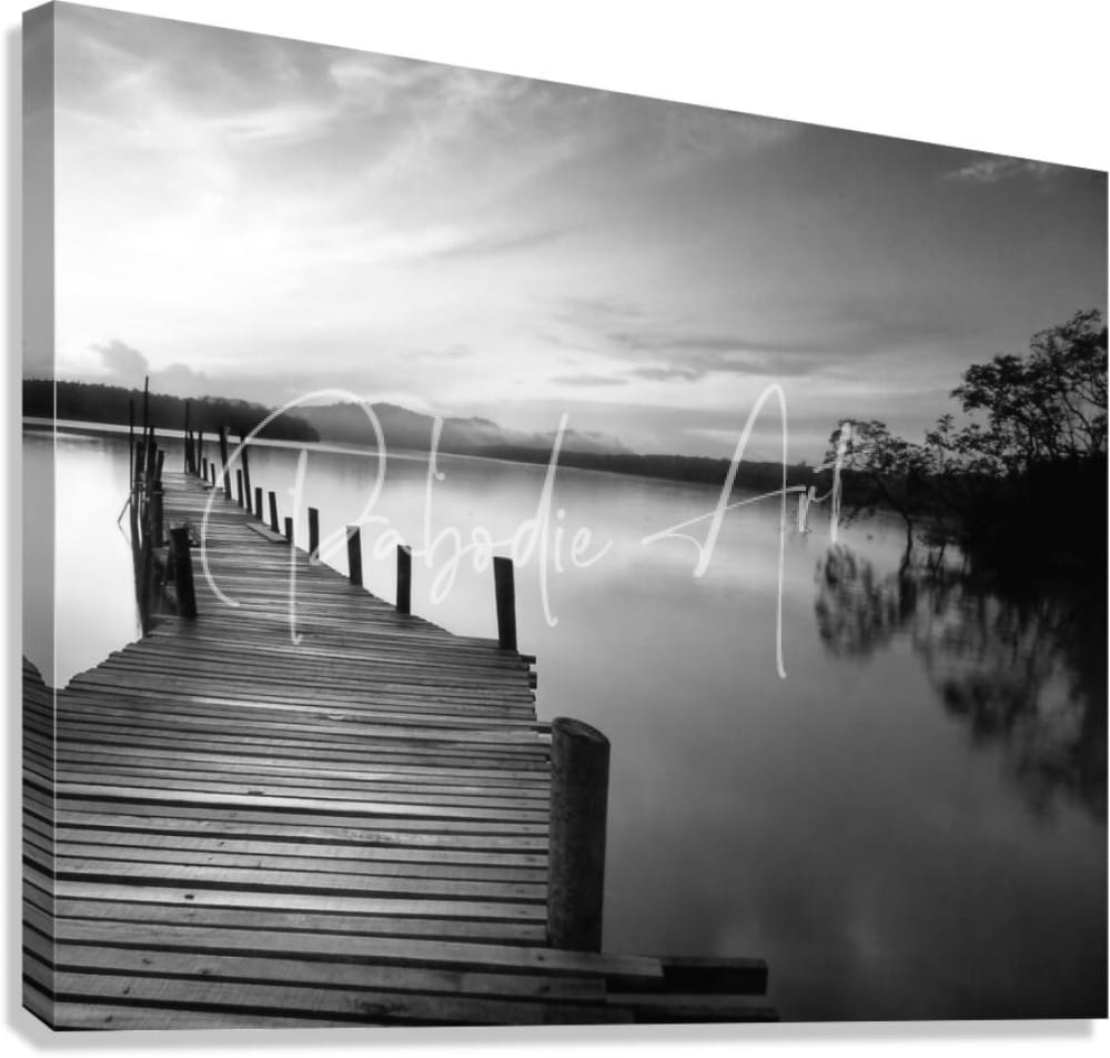 Black and white canvas print of a wooden dock extending over calm water titled Dawn Breaks Over Still Waters