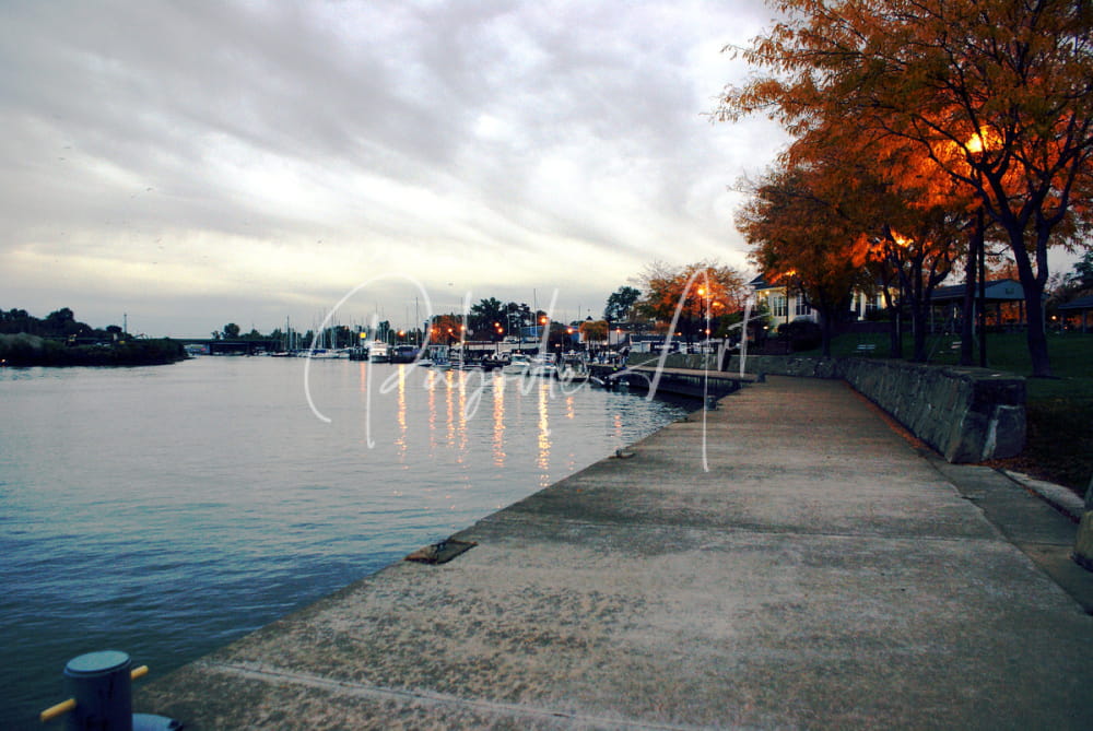 Concrete walkway beside a calm waterway under an overcast sky in dawn on the huron river product image