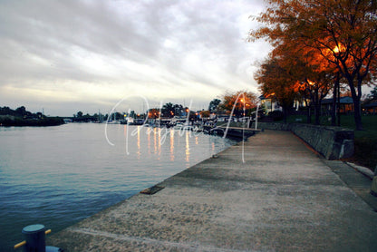 Concrete walkway beside a calm waterway under an overcast sky in dawn on the Huron River scene