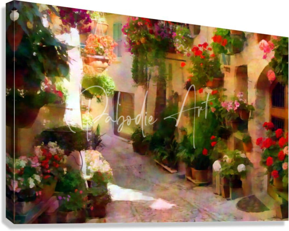 A vibrant canvas print titled flower filled cobblestone alley depicting a sunlit european alleyway with red purple and green flowers
