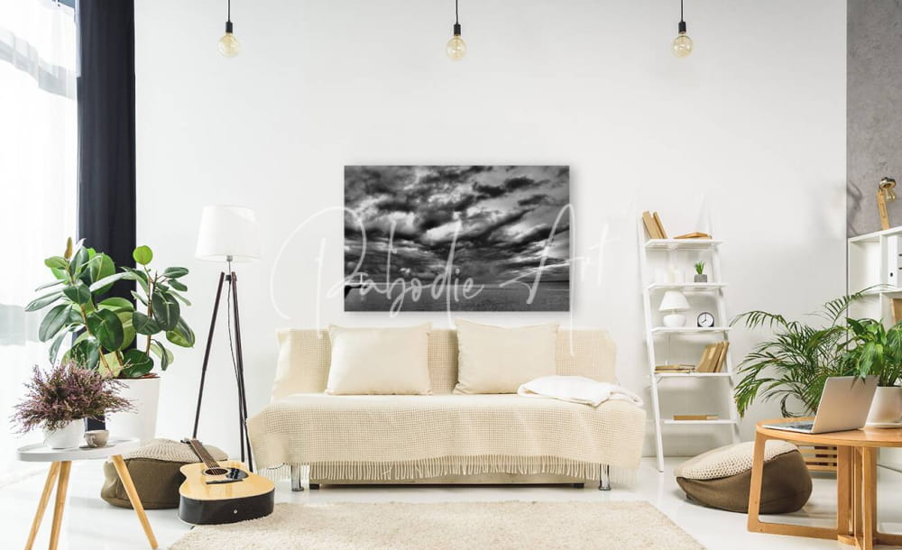 Black and white cloudscape canvas titled huron lighthouse incoming storm hanging above a beige sofa