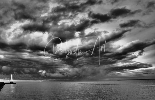 Dramatic black and white photograph of huron lighthouse on a pier under a swirling cloud sky titled incoming storm