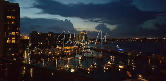 Night lights at the marina cityscape featuring illuminated skyscrapers and boats under a dark cloudy sky at night