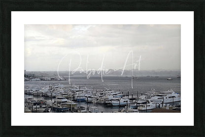 Black-framed art print of old port cove marina monochrome harbor scene with boats docked in calm waters under overcast sky