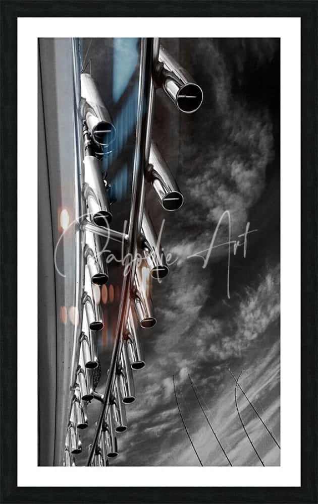 Black-framed art print of a monochrome photo showing shiny chrome rod holders exhaust pipes against a cloudy sky