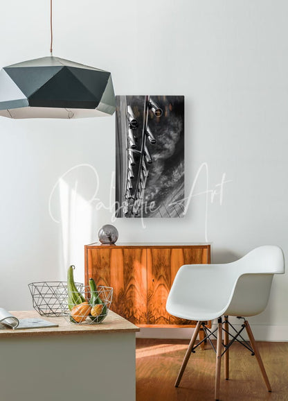 Black and white abstract metal rod holders sculpture hanging on the wall above a wooden cabinet