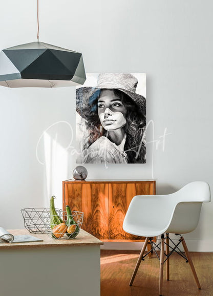 Black-and-white portrait canvas of a woman in a wide-brimmed hat titled a womans casual glance mounted on white wall