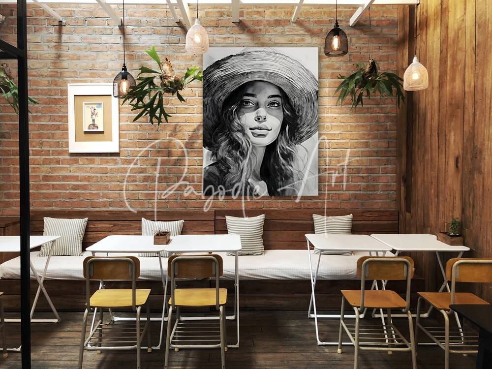 A black-and-white portrait painting of a woman wearing a wide-brimmed hat displayed on an exposed brick wall